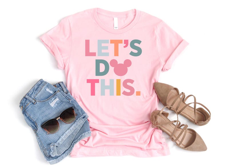 Peut inclure: T-shirt rose avec le texte "LET'S DO THIS." en lettres color&eacute;es et une t&ecirc;te de Mickey Mouse rose.