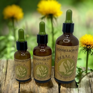 Puede incluir: Tres botellas de vidrio ámbar con goteros, etiquetadas "Raíz de diente de león Herbal Bliss 100% Natural". Las botellas están dispuestas en una fila de la más grande a la más pequeña sobre una superficie de madera. El fondo está desenfocado y muestra follaje verde y flores de diente de león amarillas.