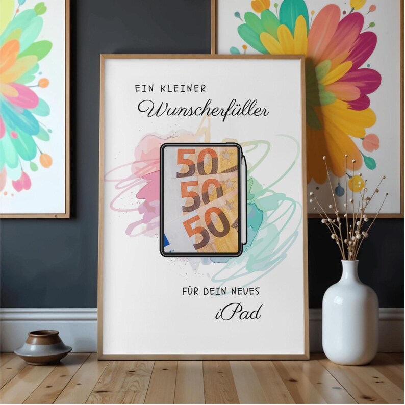 May include: A framed poster featuring the German text "EIN KLEINER Wunscherf&uuml;ller" at the top and "F&Uuml;R DEIN NEUES iPad" at the bottom. The center displays a tablet illustration showing three fifty-euro banknotes with a stylus attached to the side.