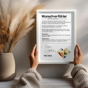 May include: A framed print with the German word "Wunscherf&uuml;ller" and its definition. The print includes the text "Happy Birthday" and "Von Sarah". The image is held by a person.