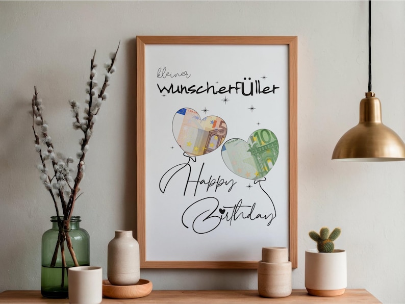 K&ouml;nnte beinhalten: Ein gerahmter Druck mit dem Text "kleiner Wunscherf&uuml;ller" und "Happy Birthday" in schwarzer Schrift. Zwei herzf&ouml;rmige Luftballons sind abgebildet, wobei einer einen 5-Euro-Schein und der andere einen 10-Euro-Schein enth&auml;lt, verziert mit Sternen.