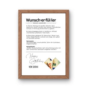 May include: A framed print with a wooden frame. The print features German text, including the word "Wunscherf&uuml;ller" and a definition. Below the text is "Happy Birthday" and "VON SARAH". A folded paper with the number 20 is in the lower right corner.