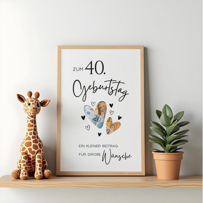 May include: A framed white poster with black text reading ZUM 40. GEBURTSTAG and EIN KLEINER BEITRAG F&Uuml;R GROBE W&Uuml;NSCHE. The design features two heart-shaped cutouts filled with Euro banknotes, surrounded by small black heart illustrations.