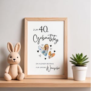 May include: A framed print with the German text Zum 40. Geburtstag, Ein kleiner Beitrag f&uuml;r gro&szlig;e W&uuml;nsche, featuring two heart-shaped cutouts filled with Euro banknotes, surrounded by small black heart illustrations on a white background.