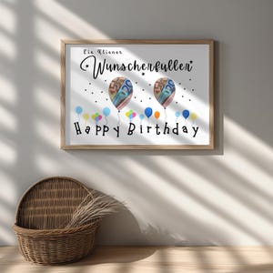 May include: A framed print with a wooden frame, featuring the words "Ein Kleiner Wunscherfuller" and "Happy Birthday". The artwork includes two balloon illustrations with money inside and colorful balloons at the bottom.