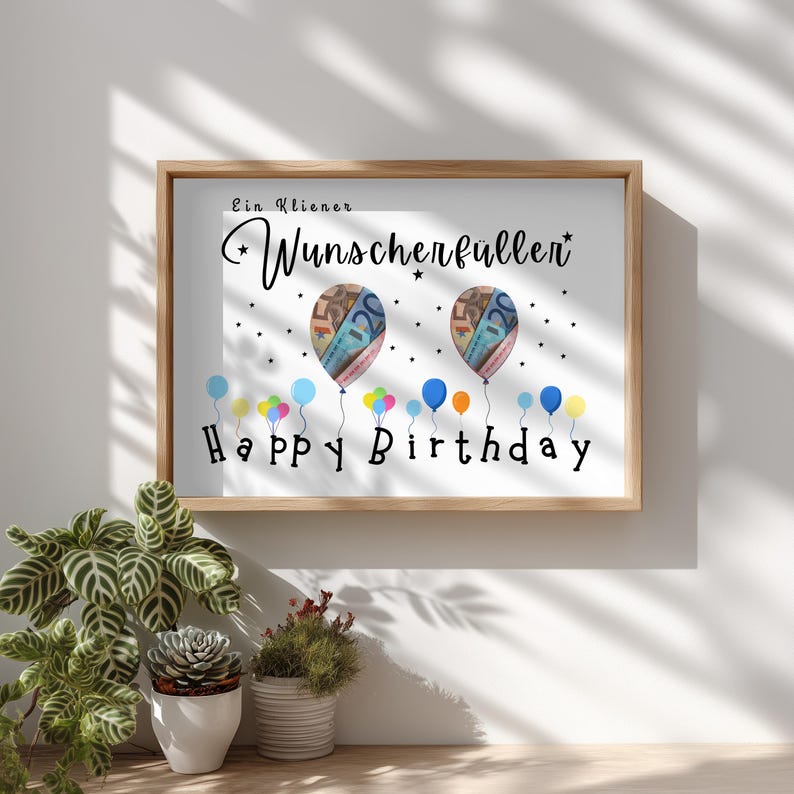 May include: A framed print with the words "Happy Birthday" in black script. Two balloon-shaped images are filled with colorful currency. Colorful balloons float below the text, and the words "Ein kleiner Wunscherf&uuml;ller" are at the top.