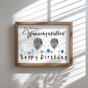 May include: A framed print with a white background features the text "Ein Kleiner Wunsch erf&uuml;llen" and "Happy Birthday". Two balloons with money designs are in the center, surrounded by colorful balloons.