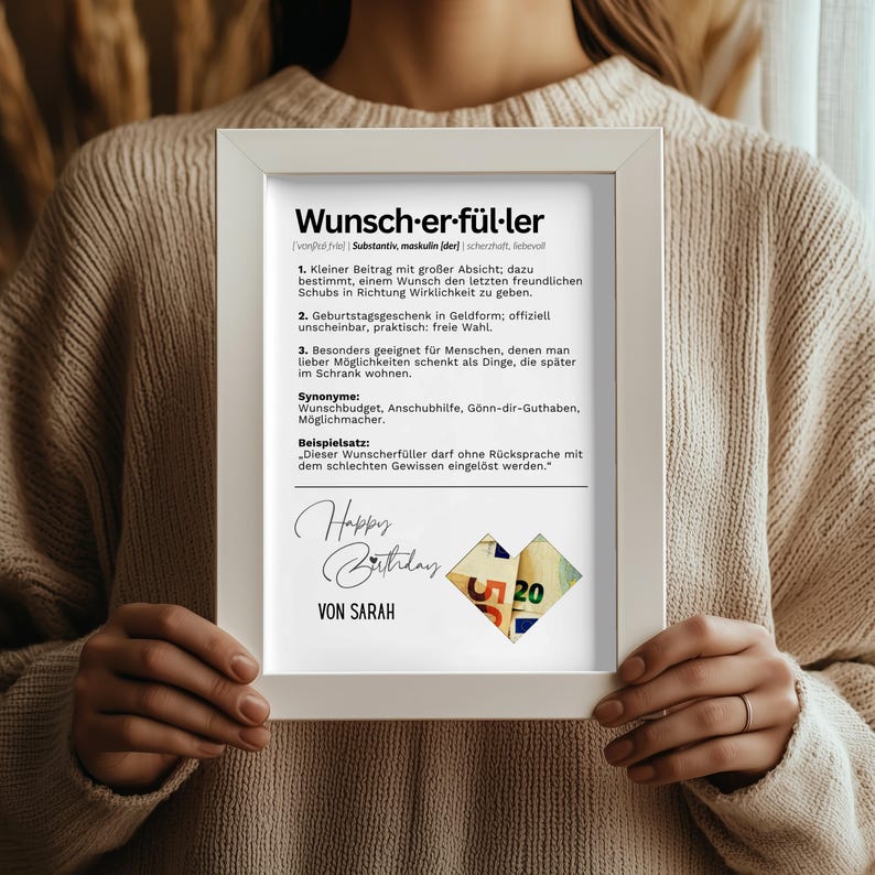 May include: A framed print with the German word "Wunsch-er-f&uuml;l-ler" and its definition. The print includes the text "Happy Birthday" and the name "VON SARAH" below a collage of money.