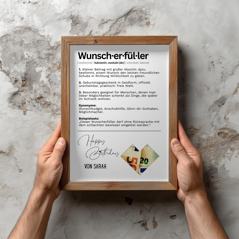 May include: A framed print with the German word "Wunscherf&uuml;ller" at the top, meaning "wish fulfiller". The print includes definitions, synonyms, and a sample sentence. The bottom features "Happy Birthday" and "Von Sarah" with a heart made of money.