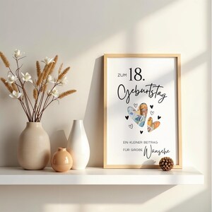 May include: A framed print with the text "ZUM 18. GEBURTSTAG" and "EIN KLEINER BEITRAG F&Uuml;R GROBE W&Uuml;NSCHE" featuring two heart-shaped cutouts filled with Euro banknotes, surrounded by small black hearts, displayed next to three ceramic vases.