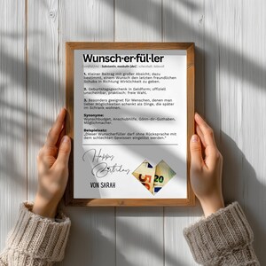 May include: A framed print with German text, including the word "Wunscherf&uuml;ller" and a definition. The print also features the words "Happy Birthday" and "Von Sarah", along with a heart-shaped design with the number 20.