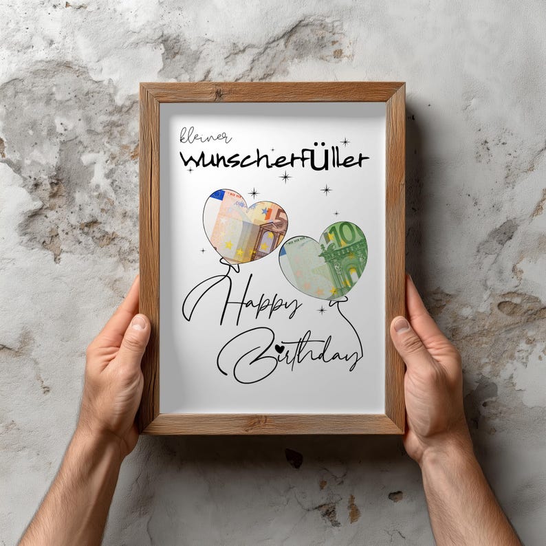 K&ouml;nnte beinhalten: Ein Holzrahmen mit einem wei&szlig;en Druck, der den schwarzen Schriftzug "kleiner Wunscherf&uuml;ller" und "Happy Birthday" in Schreibschrift zeigt. Abgebildet sind zwei herzf&ouml;rmige Luftballons, gef&uuml;llt mit einem F&uuml;nf-Euro-Schein und einem Hundert-Euro-Schein.
