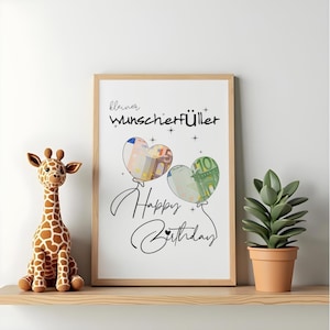K&ouml;nnte beinhalten: Ein gerahmter Druck mit dem Text "kleiner Wunscherf&uuml;ller" und "Happy Birthday" in schwarzer Schrift. Zwei herzf&ouml;rmige Luftballons sind abgebildet, wobei einer einen 50-Euro-Schein und der andere einen 10-Euro-Schein im Inneren enth&auml;lt.