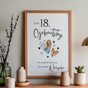 May include: A framed white poster with black text reading Zum 18. Geburtstag and Ein kleiner Beitrag f&uuml;r gro&szlig;e W&uuml;nsche. The design features two heart-shaped cutouts filled with Euro banknotes, surrounded by small black hand-drawn heart icons.