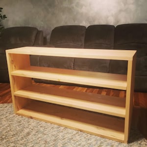 May include: A light wood shelf unit with three shelves. The shelf unit is made of unfinished wood and has a simple, modern design.
