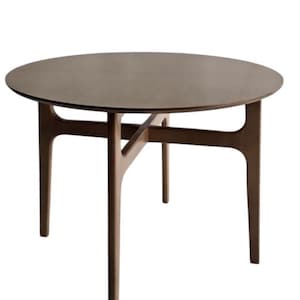 Op de afbeelding: Een ronde eettafel met een glad, donkerbruin houten oppervlak en een onderstel met vier poten die verbonden zijn door een centrale kruisvormige steunstructuur. De tafel heeft een egale afwerking en een cirkelvormig tafelblad.