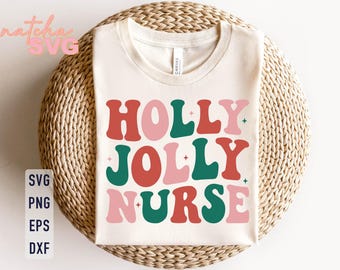 May include: Cream-colored t-shirt with the words "HOLLY JOLLY NURSE" in a retro font. The text is in red, pink, and green, with small star accents. The shirt is displayed on a woven, circular surface.