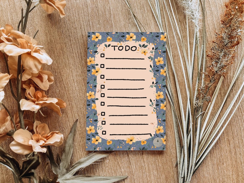 May include: A blue and yellow floral patterned notepad with the word "TO DO" written in black at the top. The notepad has a lined section for writing tasks.
