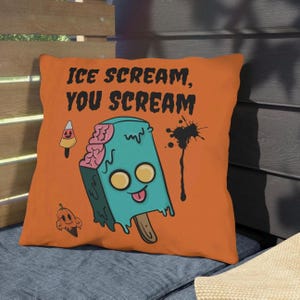 May include: Orange throw pillow with the text "ICE SCREAM, YOU SCREAM". The pillow features a cartoon popsicle with a zombie theme, with teal ice cream, pink brains, and yellow eyes. Additional Halloween-themed graphics are included.