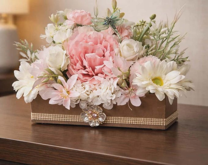 Eye-catching artificial pink and cream flowers in full bloom in a gold box with bling.