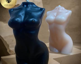 Puede incluir: Dos velas decorativas con forma de torso humano. Una vela es negra y la otra es de color melocotón claro.