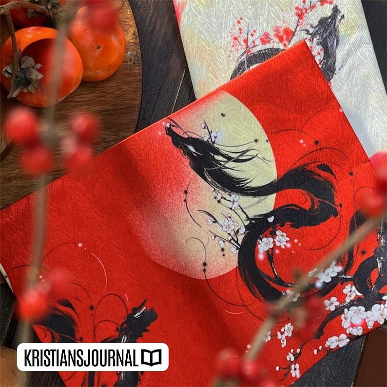 K&ouml;nnte beinhalten: Dekorativer Stoff in Rot und Creme mit japanisch inspiriertem Design. Der rote Stoff zeigt eine schwarze Drachenillustration mit Vollmond und Kirschbl&uuml;ten. Der cremefarbene Stoff hat ein &auml;hnliches Design. Der Text "KRISTIANSJOURNAL" ist sichtbar.