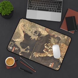 Peut inclure: Tapis de souris rectangulaire avec une illustration détaillée d'un dragon et d'un tigre en scène de combat. L'œuvre d'art est dans les tons beige, marron et noir, avec une bordure noire. Une souris d'ordinateur blanche est posée sur le tapis.