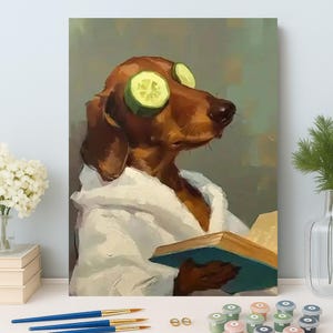 Può includere: Un bassotto con un accappatoio bianco e fette di cetriolo sugli occhi, che tiene in mano un libro. Il cane è dipinto in una posa rilassata, con uno sfondo verde chiaro. Pennelli e vasetti di vernice in primo piano.