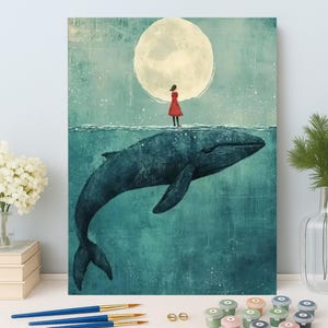 Op de afbeelding: Een surrealistisch schilderij toont een walvis in turquoise water, met een persoon in een rode jurk die erop staat, onder een grote maan. Penselen, verfpotten en een vaas met bloemen op de voorgrond. Het kunstwerk roept een droomachtige kwaliteit op.