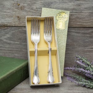May include: Two silver forks in a yellow and green box with the text "Vintage Cutlery Product" on the box.