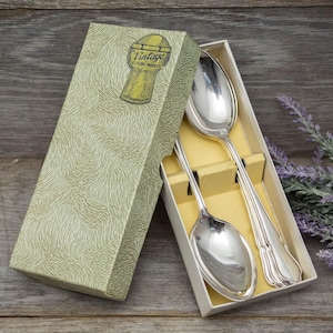 May include: Two silver spoons in a box with a green and white patterned lid. The box has a label that reads "Vintage Cutlery Product."
