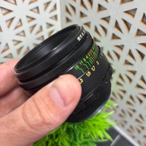 Peut inclure: Un objectif d'appareil photo noir avec une bague de mise au point stri&eacute;e et une s&eacute;rie de marquages color&eacute;s. L'objectif porte les chiffres "16 11 8 5.6" imprim&eacute;s sur le dessus. L'objectif est con&ccedil;u pour &ecirc;tre utilis&eacute; avec un appareil photo.