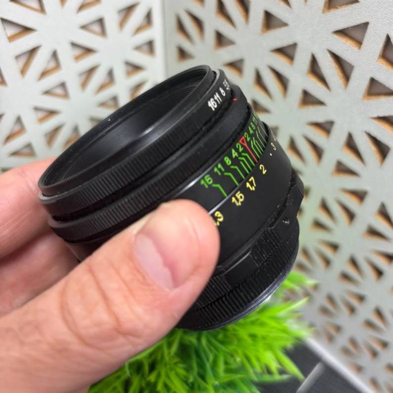 Peut inclure: Un objectif d'appareil photo noir avec une bague de mise au point stri&eacute;e et une s&eacute;rie de marquages color&eacute;s. L'objectif porte les chiffres "16 11 8 5.6" imprim&eacute;s sur le dessus. L'objectif est con&ccedil;u pour &ecirc;tre utilis&eacute; avec un appareil photo.