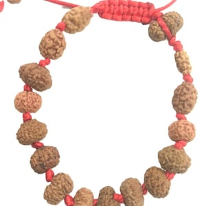 Può includere: Un braccialetto di corda rossa con perline marroni. Le perline sono fatte di materiali naturali e hanno una texture ruvida.