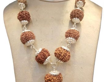 May include: A silver chain necklace with brown beads. The beads are round and have a textured surface. The necklace has a silver pendant with a floral design.