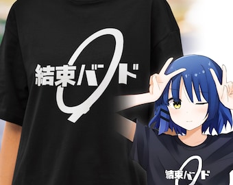 May include: Black t-shirt with white Japanese text and a stylized design. The text is in a bold, sans-serif font. The shirt is worn by a person. A cartoon image of a girl wearing the same shirt is also visible.