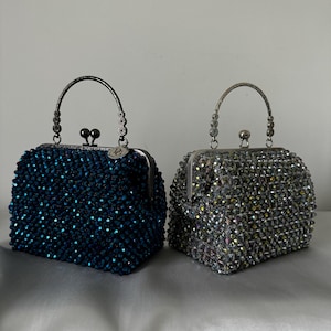 May include: Two beaded evening bags with silver metal frames and handles. One bag is blue and the other is silver.
