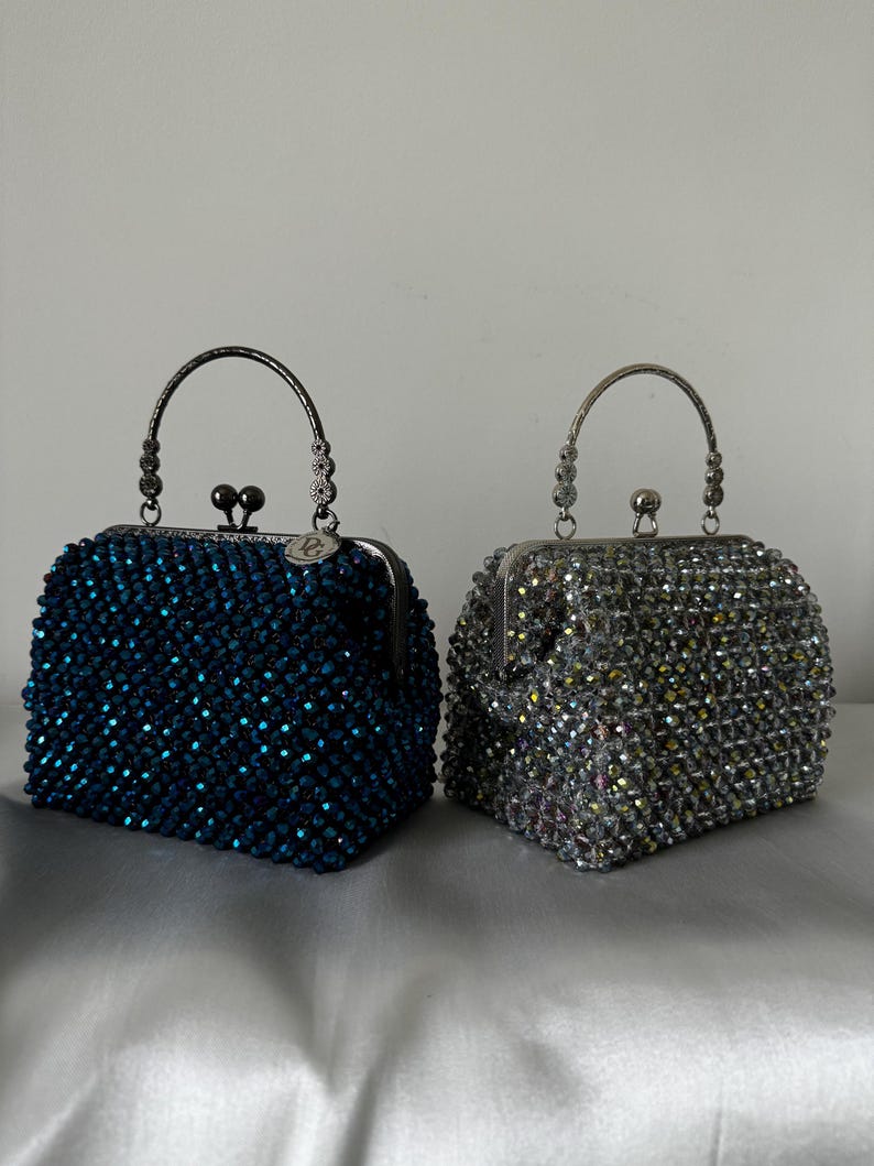 May include: Two beaded evening bags with silver metal frames and handles. One bag is blue and the other is silver.