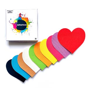 Può includere: Un set di 10 cerotti adesivi a forma di cuore in vari colori, tra cui nero, blu, marrone, bianco, verde, arancione, giallo, rosa, viola e rosso. I cerotti sono disposti in fila, con il cuore rosso in alto. Il testo "Dpatch" è visibile su una scatola sullo sfondo.
