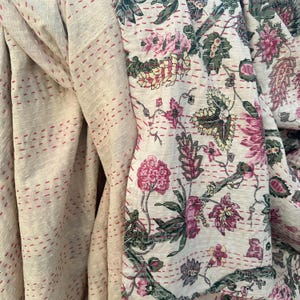 Può includere: Trapunta kantha color crema con un motivo floreale nei toni del rosa, verde e viola. La trapunta presenta dettagli cuciti a mano con filo rosso. Le trapunte kantha sono una forma d'arte tessile tradizionale.