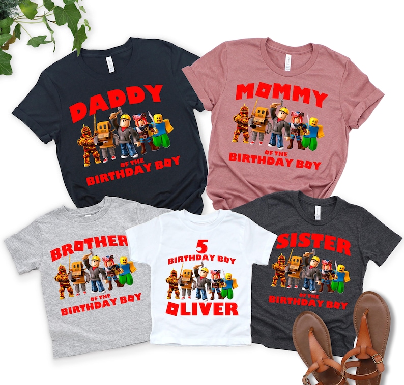 Op de afbeelding: Vijf T-shirts met korte mouwen met verjaardagsafbeeldingen. De shirts zijn marineblauw, mauve, grijs, wit en houtskool. Elk shirt heeft een andere tekst: "Daddy", "Mommy", "Brother", "5 Birthday Boy Oliver" en "Sister".