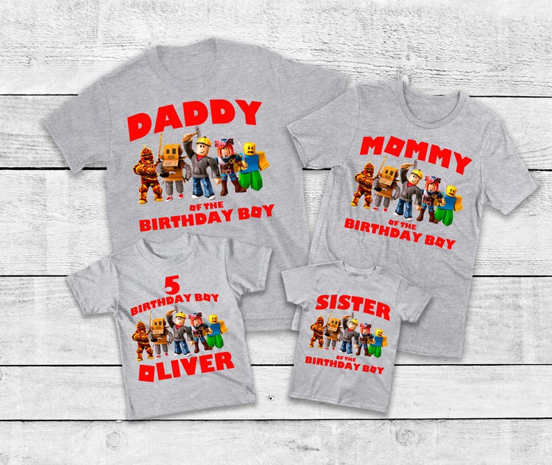 Op de afbeelding: Vier grijze t-shirts met rode tekst en cartoonkarakterafbeeldingen. De shirts lezen "DADDY", "MOMMY", "5 BIRTHDAY BOY OLIVER" en "SISTER". Elk shirt heeft een ander ontwerp.
