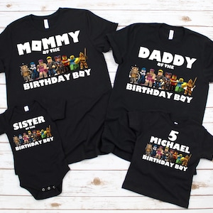 May include: Black t-shirts and a onesie with white text and colorful character graphics. The shirts read "Mommy of the Birthday Boy," "Daddy of the Birthday Boy," and "5 Michael Birthday Boy." The onesie says "Sister of the Birthday Boy."