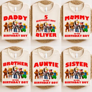 Op de afbeelding: Zes beige T-shirts met rode tekst en een cartoonafbeelding. De shirts zeggen "DADDY", "5 BIRTHDAY BOY OLIVER", "MOMMY", "BROTHER", "AUNTIE" en "SISTER". Elk shirt heeft een afbeelding van stripfiguren.