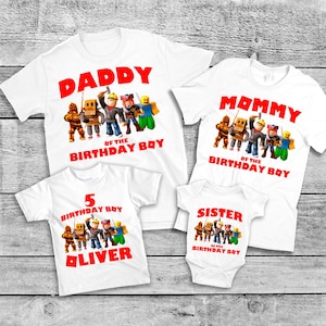 Op de afbeelding: Witte T-shirts met rode tekst en een cartoonafbeelding. De shirts lezen "DADDY", "MOMMY", "5 BIRTHDAY BOY OLIVER" en "SISTER" met "OF THE BIRTHDAY BOY" eronder. De afbeelding toont verschillende stripfiguren.