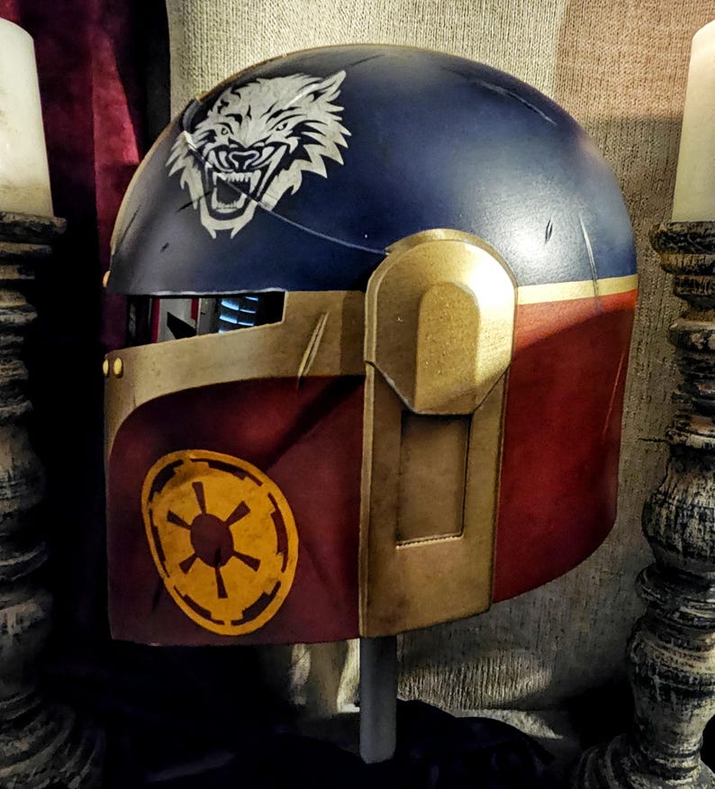 May include: A custom-painted helmet with a navy blue top and burgundy lower section. A white wolf graphic is on the top, and a yellow emblem is on the side. Gold-colored accents and details are present throughout the helmet.