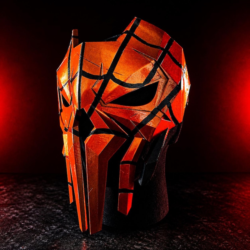K&ouml;nnte beinhalten: Eine orange-schwarze geometrische Maske mit einem bedrohlichen Design. Die Maske hat scharfe Winkel und Linien, mit einem dunklen Innenraum und einer strukturierten Oberfl&auml;che. Geeignet f&uuml;r Cosplay oder Kost&uuml;me.