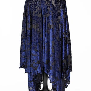 Pode incluir: Uma saia de veludo azul e preto com um padr&atilde;o floral. A saia &eacute; assim&eacute;trica, com uma frente mais longa e uma parte de tr&aacute;s mais curta. A saia tem uma bainha com babados.