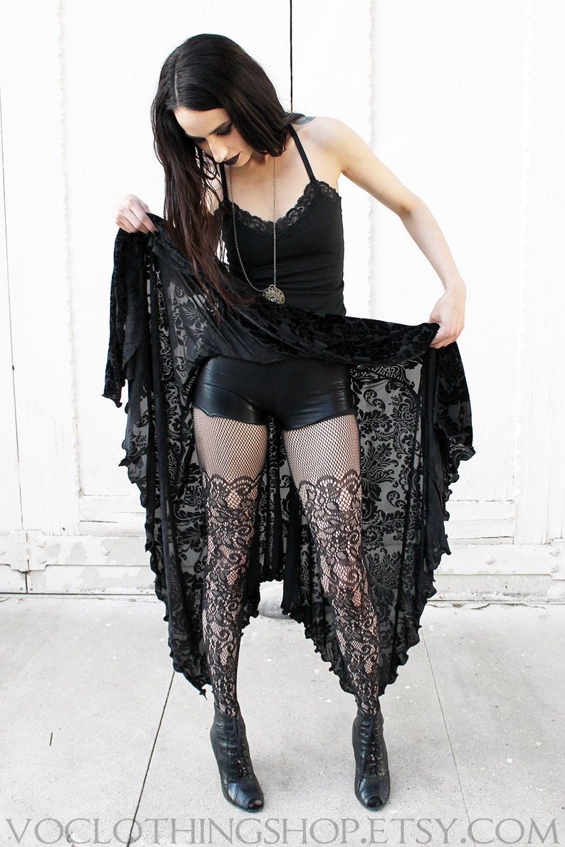 May include: Black lace skirt with a black tank top and black fishnet stockings. The skirt is a high-low style with a shorter front and a longer back. The stockings have a lace pattern at the top.