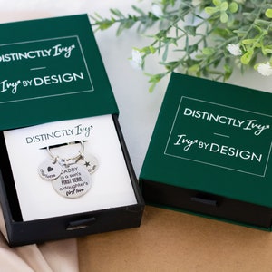 DistinctlyIvy green drawer gift box and silver personalized keyring inside laying on white fabric with green leaves and white flowers in the background